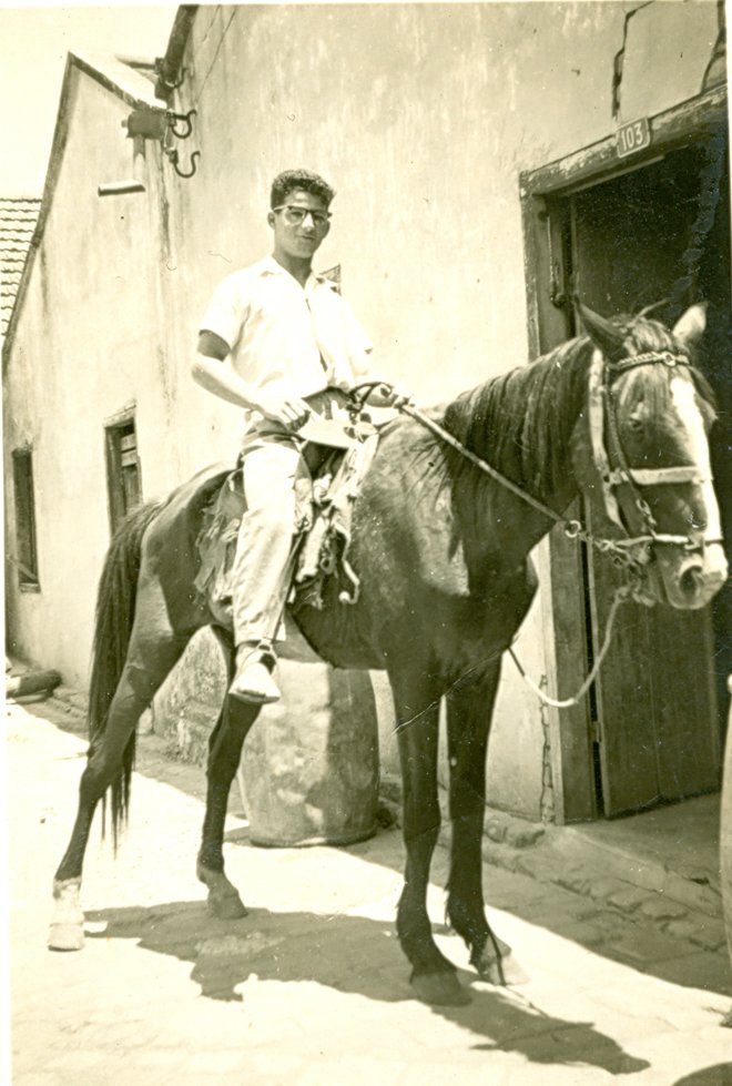 Rubens Frazato a cavalo, em frente da porta da beneficiadora de arroz e do moinho de fubá, do seu pai João, na década de 1940 (Acervo Casa da Memória Padre Gomes)