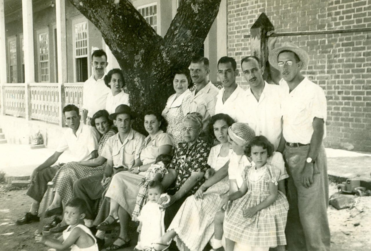 Darcy e Maria do Carmo (Ik) da esquerda para a direita sentados, juntos com os membros da família Machado de Souza, na década de 1940, em frente à sede da Fazenda da Barra, em Guedes (Acervo Casa da Memória Padre Gomes)