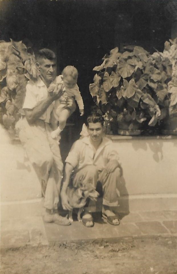 Imigrante português Antonio carregando a neta Gislaine com o filho Moacir em frente à casa comprada no ano de 1940 (Acervo da família Mathias)