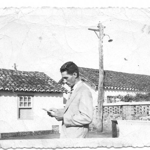 Guarino Zanon realizando a leitura na missa realizada na Fazenda Santa Cruz (elas aconteciam no terreiro onde secavam café) ao fundo são as casas que existiam perto da sede da fazenda. A primeira casa à direita era onde Marici morava
